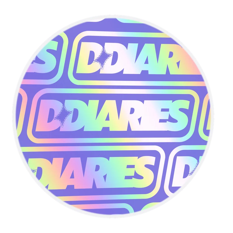 A 77mm circular holographic sticker, repeating DDIARIES wordmarks in purple ink over rainbow foil. Drag it to shift the colours.